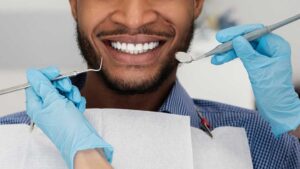 A toddler sits on a parent's lap as a dental professional gently examines the child's first teeth.