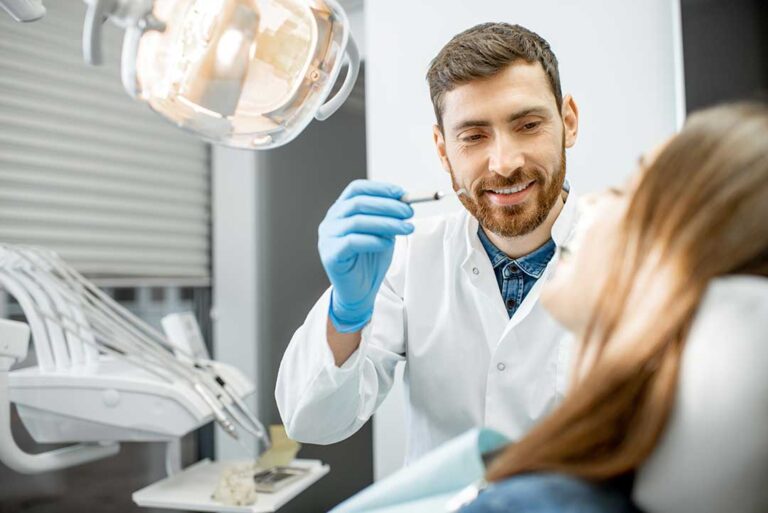 A person brushing teeth with a soft-bristled toothbrush over a bathroom sink, focusing on the gumline.
