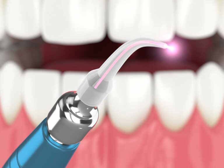 Person gently cleaning their tongue beside a toothbrush, glass of water, and dental floss
